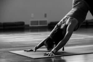 Black and white image of woman in downward dog post, stress reduction